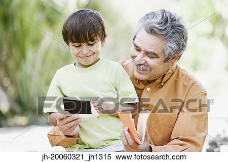 Father and son looking at photographs outdoors View Large Photo Image Stock Photography - Father and son looking at photographs outdoors. Fotosearch