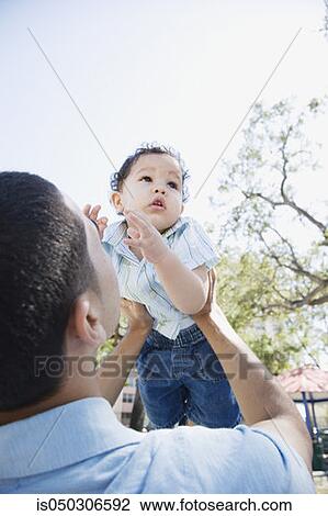 Stock Image - Father holding baby up in air. Fotosearch