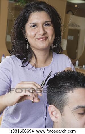 Picture - Hispanic female hairstylist cutting hair. Fotosearch