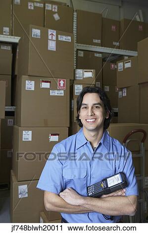 Stock Image - Hispanic male warehouse worker with barcode scanner. Fotosearch