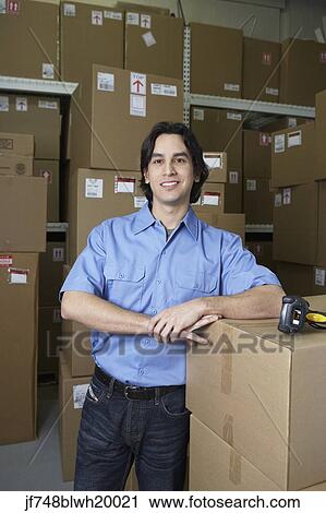 Stock Image - Hispanic male warehouse worker with boxes. Fotosearch