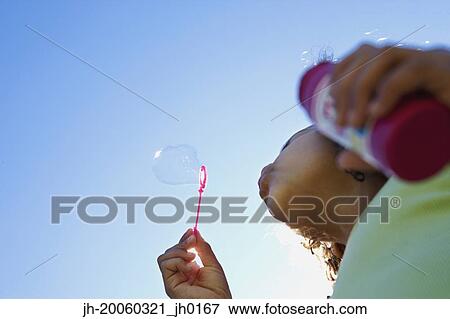 Low angle view of girl blowing bubbles View Large Photo Image Stock Photo - Low angle view of girl blowing bubbles. Fotosearch