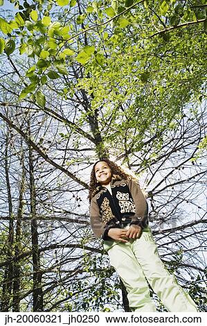 Low angle view of young girl under tree View Large Photo Image Stock Image - Low angle view of young girl under tree. Fotosearch