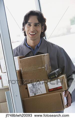 Stock Image - Male delivery person with stack of boxes. Fotosearch