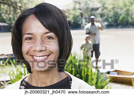 Middle-aged African woman smiling with family in background View Large Photo Image Stock Image - Middle-aged African woman smiling with family in background. Fotosearch