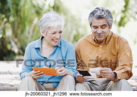 Middle-aged couple looking at photographs outdoors View Large Photo Image Stock Photograph - Middle-aged couple looking at photographs outdoors. Fotosearch