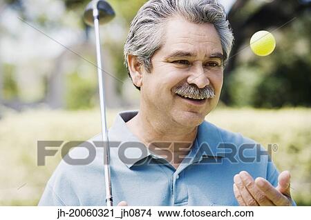 Picture - Middle-aged man with golf club and golf ball. Fotosearch