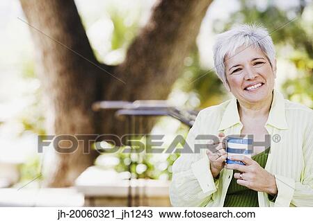 Middle-aged woman with coffee smiling outdoors View Large Photo Image Stock Image - Middle-aged woman with coffee smiling outdoors. Fotosearch