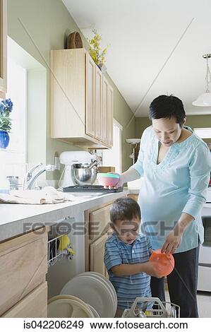 Stock Photo - Mother and young son putting dishes in dishwasher. Fotosearch