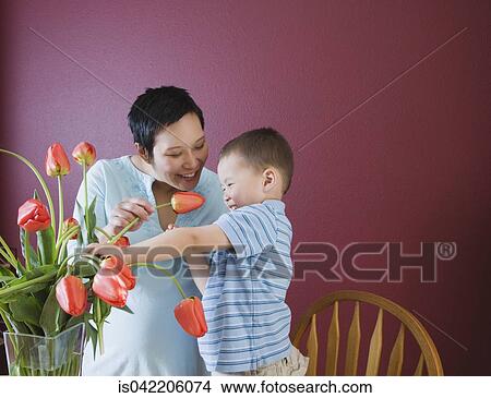 Picture - Mother and young son putting flowers in vase. Fotosearch
