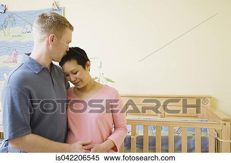 Pregnant couple hugging in nursery View Large Photo Image Stock Photography - Pregnant couple hugging in nursery. Fotosearch