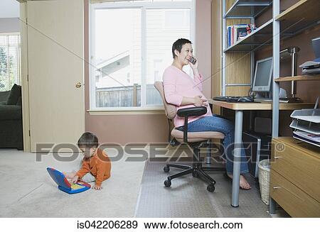 Pregnant woman working at home with young son View Large Photo Image Stock Photo - Pregnant woman working at home with young son. Fotosearch