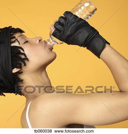 Studio shot of African woman drinking bottle of water View Large Photo Image Stock Photo - Studio shot of African woman drinking bottle of water. Fotosearch