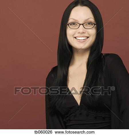Stock Photograph - Studio shot of woman smiling and wearing eye glasses. Fotosearch