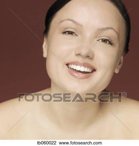 Stock Image - Studio shot of woman smiling with bare shoulders. Fotosearch