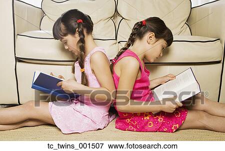 Two young sisters reading back to back View Large Photo Image Stock Photo - Two young sisters reading back to back. Fotosearch