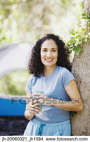 Woman leaning on tree next to tent View Large Photo Image Picture - Woman leaning on tree next to tent. Fotosearch