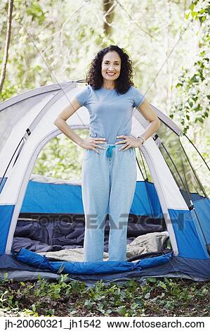 Stock Image - Woman standing next to tent. Fotosearch