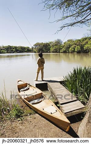Woman standing on dock next to canoe View Large Photo Image Stock Photograph - Woman standing on dock next to canoe. Fotosearch