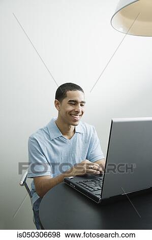 Stock Photo - Young African man using laptop. Fotosearch