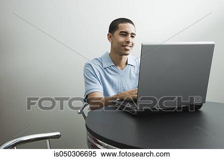 Stock Photography - Young African man using laptop. Fotosearch