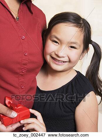 Stock Photo - Young Asian girl giving mother gift. Fotosearch