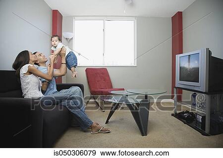 Stock Photo - Young couple playing with baby on sofa. Fotosearch
