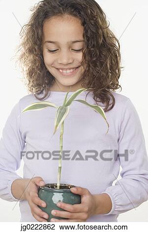 Stock Image - Young girl holding potted plant. Fotosearch