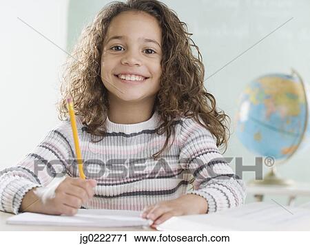 Stock Image - Young girl in classroom smiling. Fotosearch