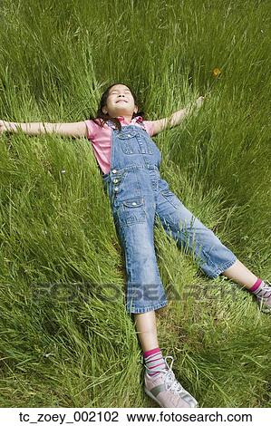 Young girl laying in tall grass View Large Photo Image Stock Image - Young girl laying in tall grass. Fotosearch