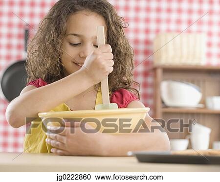 Stock Image - Young girl mixing batter in kitchen. Fotosearch