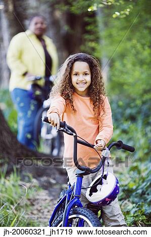 Stock Photo - Young girl on bicycle in woods. Fotosearch