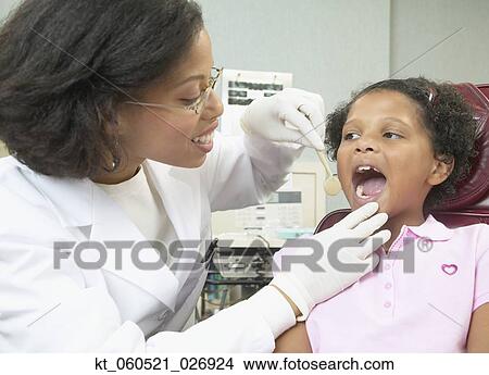 African female dentist examining young female patient View Large Photo Image Picture - African female dentist examining young female patient. Fotosearch