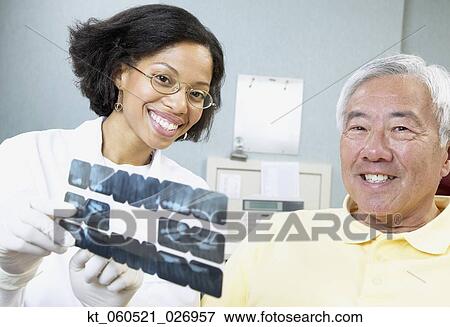 African female dentist showing x-rays to senior male patient View Large Photo Image Stock Photo - African female dentist showing x-rays to senior male patient. Fotosearch