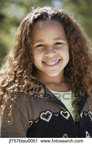 Stock Image - African girl with braces smiling outdoors. Fotosearch