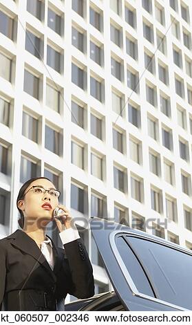 Asian businesswoman using cell phone next to car View Large Photo Image Stock Photograph - Asian businesswoman using cell phone next to car. Fotosearch
