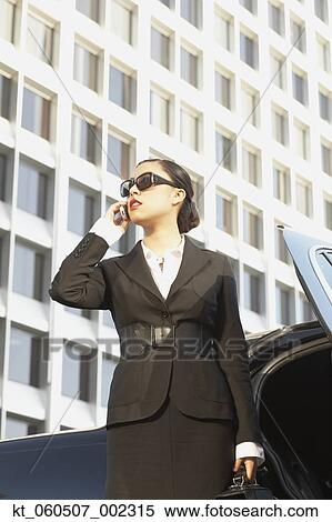 Asian businesswoman using cell phone next to car View Large Photo Image Stock Photography - Asian businesswoman using cell phone next to car. Fotosearch