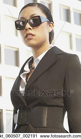 Stock Image - Asian businesswoman wearing sunglasses outdoors. Fotosearch
