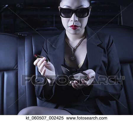 Stock Photography - Asian businesswoman with make up in back seat of car. Fotosearch