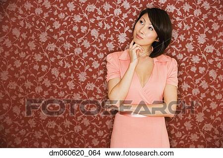 Asian woman thinking in front of floral wallpaper View Large Photo Image Picture - Asian woman thinking in front of floral wallpaper. Fotosearch