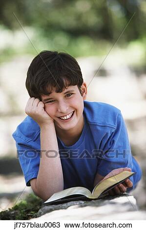 Stock Image - Boy smiling with book outdoors. Fotosearch