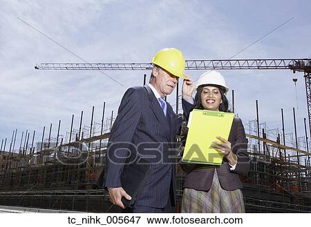 Businesswoman and businessman wearing hard hats at construction site View Large Photo Image Stock Photo - Businesswoman and businessman wearing hard hats at construction site. Fotosearch
