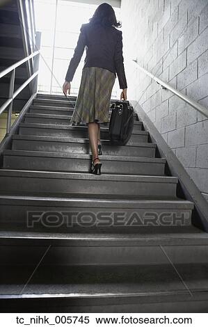 Stock Photography - Businesswoman walking up stairs with briefcase. Fotosearch