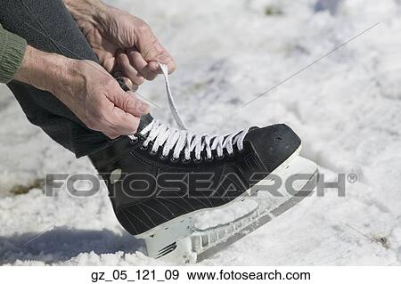 Stock Photo - Close up of man lacing ice skate. Fotosearch