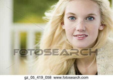 Stock Photo - Close up of young woman with hair blowing outdoors. Fotosearch