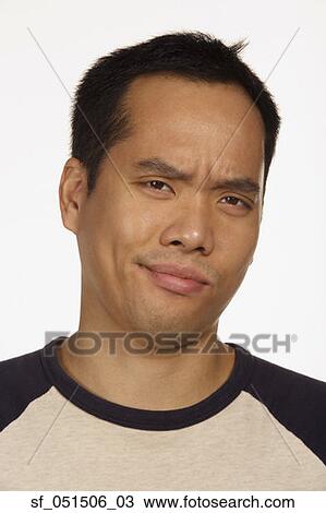 Stock Image - Close up studio shot of Asian man looking skeptical. Fotosearch