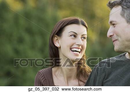 Couple looking at each other and laughing outdoors View Large Photo Image Stock Image - Couple looking at each other and laughing outdoors. Fotosearch