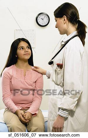 Stock Photo - Female doctor with hand on young female patient's shoulder. Fotosearch