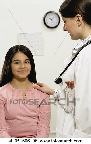 Stock Photograph - Female doctor with hand on young female patient's shoulder. Fotosearch