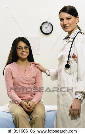 Stock Photography - Female doctor with hand on young female patient's shoulder. Fotosearch